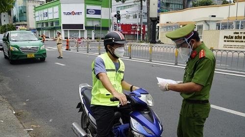 Một người đi xe gắn máy đang xuất trình giấy tờ tại chốt kiểm soát.